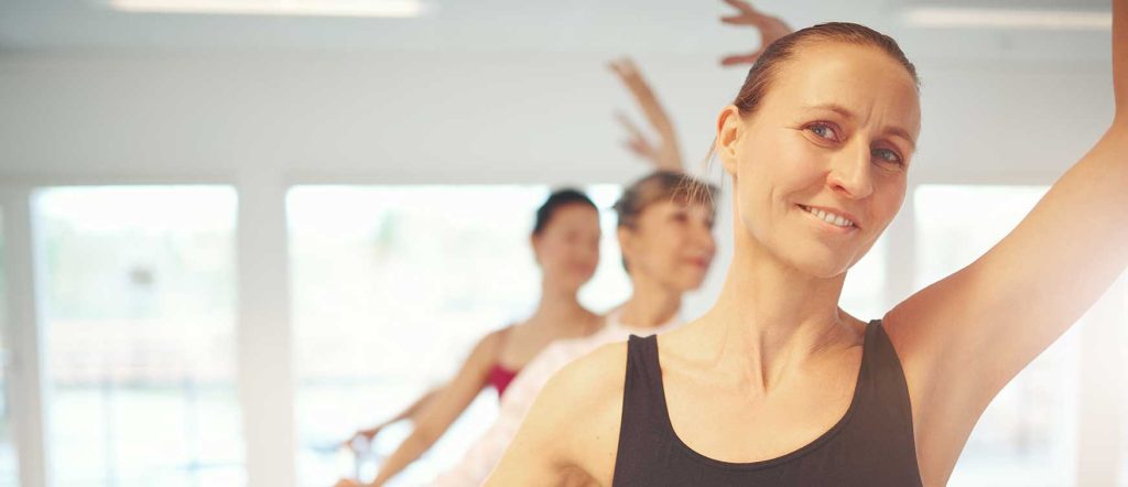 Adult ballet class in Huddersfield at Pennine Academy of Dance. Older woman facing the camera while stood at a ballet barre in a ballet class.